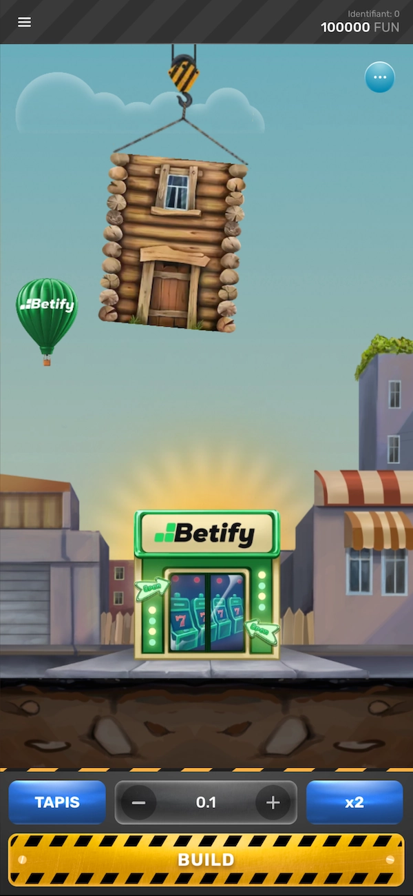 &Eacute;cran du jeu de la tour en mode d&eacute;mo sur Betify qui montre un &eacute;tage suspendu par une grue pr&ecirc;t &agrave; &ecirc;tre pos&eacute;, logo Betify visible sur un magasin au centre et sur une montgolfi&egrave;re verte &agrave; gauche, avec un solde affich&eacute; &agrave; 100000 FUN en haut &agrave; droite, une mise r&eacute;gl&eacute;e &agrave; 0.1 avec boutons TAPIS et x2 en bas, bouton BUILD jaune et noir pr&ecirc;t &agrave; lancer la construction.